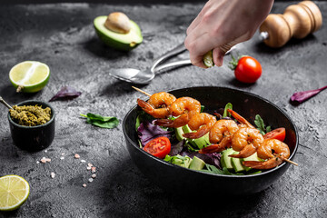 Vegetarian vegetable low carb lunch bowl with avocado, fresh salad, grilled shrimps and pesto sauce. Concept of healthy eating. top view