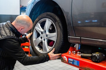 Mechanic in a car repair shop removing a wheel from a vehicle