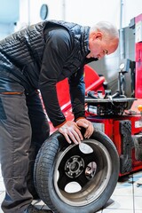 Mechanic in a car repair shop removing a tire from a vehicle's rim