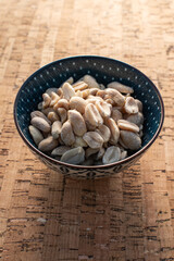 blue bowl with unsalted peeled peanuts on cork