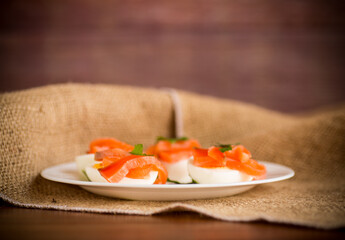 halves of boiled eggs with pieces of salted salmon