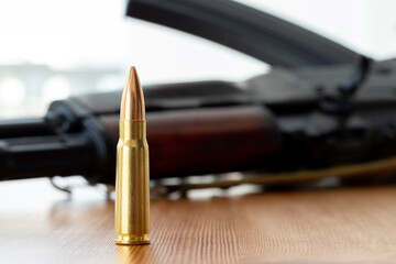 One bullet against blurred Kalashnikov assault rifle background. Cartridge 7.62 caliber for ak 47...