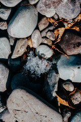 the snow melts on the pebble river bank