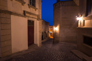 narrow street in the old town at night with lights 
