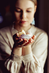 Young european girl holding a gemstone with boths hands in front of her. Mystical woman. Occult, witchcraft scene. Close up paranormal portrait.