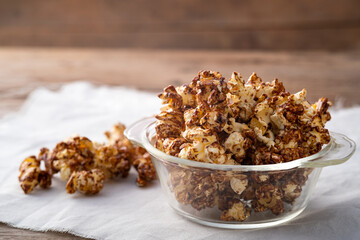 Chocolate popcorn in glass bowl on wooden table background