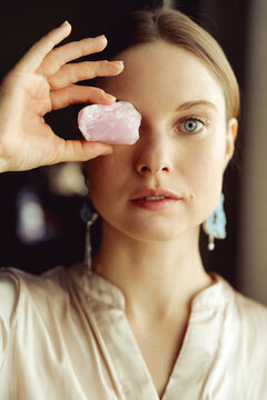 Young european girl holding a gemstone in hand in front of her. Looking towards the camera. Mystical woman..