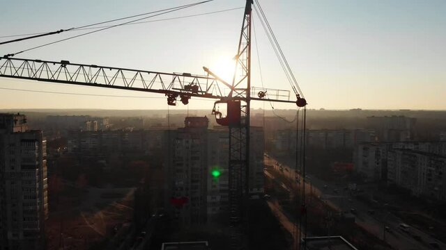 Drone shot of a crane boom or boom at a construction site during sunset. Close-up view of a boom crane lifting heavy materials at a construction site in northern Europe. Crane operator in the cockpit