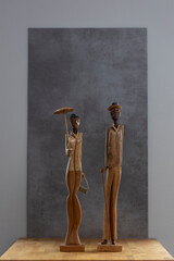 Stylish contemporary interior setting with tall slender Cuban figurine souvenirs with a woman holding a parasol and a man with cigar. Studio travel memorabilia low key object still life.