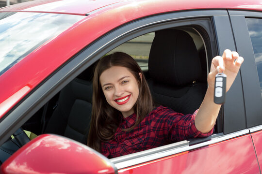 Driver woman smiling showing new car keys and car. Happy woman driver showing car keys and leaning on car door