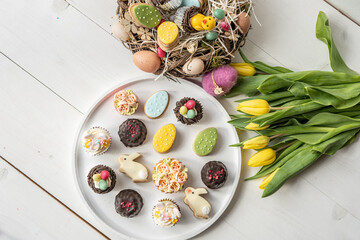 cute colorful spring easter egg shape cake tartlet muffin cupcake with yellow tulips easter concept  - 421259538