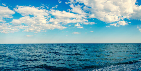 Obraz premium Seascape panorama wavy blue sea and sky with clouds
