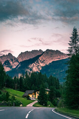 Road By Trees And Mountains Against Sky At Sunset