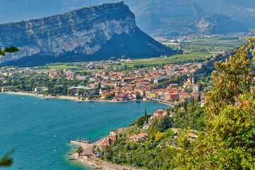 Fototapeta na wymiar Panoramic view on Lake Garda from the Busatte-Tempesta trail near Nago-Torbole with the iron staircase, Torbole town surrounded by mountains in the summer time,Italy