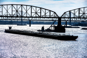Towboat pushing dry bulk cargo barge under bridges up Mississippi River. Shipping grain corn during harvest season, cargo, food, raw, transportation, agriculture, agricultural, tow, marine, maritime © Jon