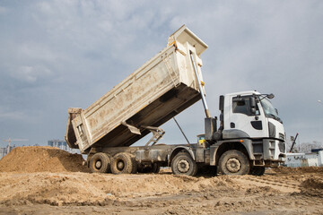 dump truck at work on a construction site. The process of transporting and unloading soil on a construction machine. Excavation