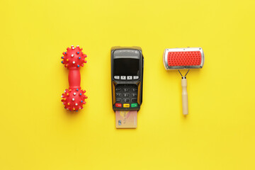 Payment terminal with credit card and pet care accessories on color background