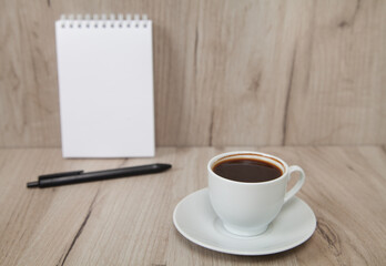 Notebook, pen and coffe, wooden background.