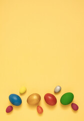 Colorful easter eggs on yellow background flat lay vertical