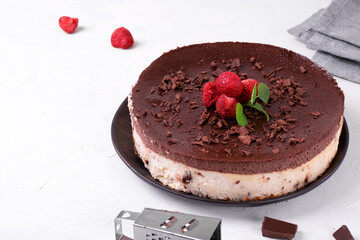 Two-layered cheesecake with cottage cheese and chocolate topped with berries. Gluten free dessert on the white table
