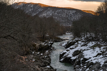 Snowy mountain river on sunset. Green color water