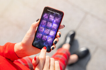 Person using astrology app on phone and reading daily horoscopes