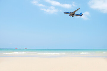 Fototapeta na wymiar Summer background. Blue sky and white sand on the beach with a boat and airplane flying on the sky. Background in the vacation in Summer time.