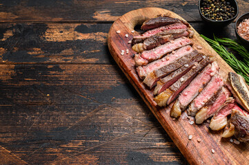 Grilled cowboy or rib eye beef steak with herbs and spices.  Wooden dark background. Top view. Copy space - obrazy, fototapety, plakaty