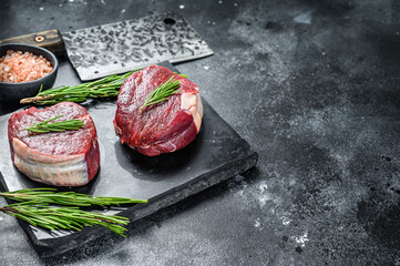 Raw steak Tenderloin fillet on a stone board. Black background. Top view. Copy space\