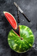 Red ripe watermelon with cut-out slices. Black background. Top view