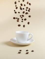 Coffee beans are flying into a white espresso cup on a yellow background. Flying food concept.