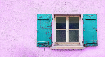 Fenster mit türkisfarbene alten und mit Spinnweben gehangenen Fensterläden. Die  Hausfassade ist rosarot.