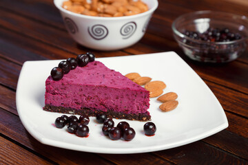 A piece of blackcurrant cake on a white plate on a wooden background