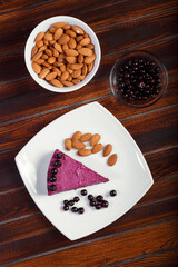 A piece of blackcurrant cake on a white plate on a wooden background