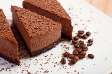 A piece of chocolate cake on a white plate on a wooden background