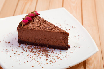 A piece of chocolate cake on a white plate on a wooden background
