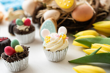 cute colorful spring easter egg shape cake tartlet muffin cupcake with yellow tulips easter concept 