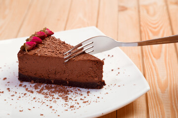 A piece of chocolate cake on a white plate on a wooden background