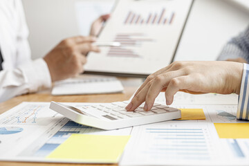 Business women are pressing a calculator to check together with male business partners, they are documenting company finances and verifying the accuracy of the information. Financial concept.