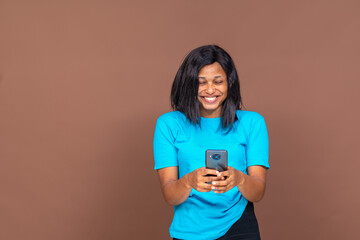 excited and happy young black lady holding her smartphone, browsing online or reading a message concept