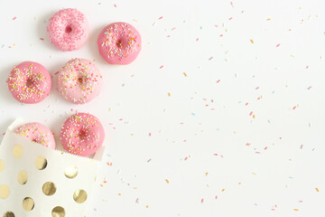 Pink donuts with sprinkles in paper bag. Calories, sugar, sweets concept. Space for text.