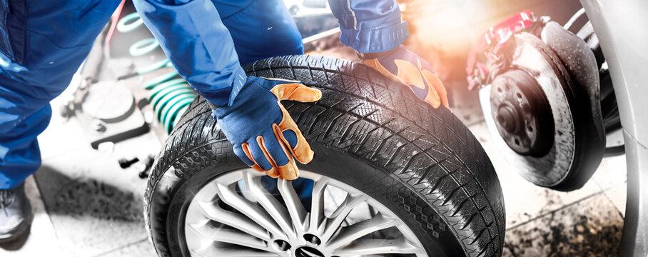 Auto mechanic working in garage and changing wheel alloy tire.