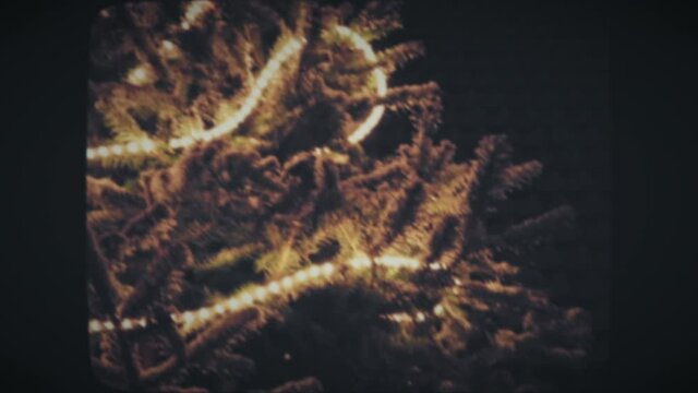 Decorated with lights Christmas tree during winter snowfall at night. Vintage Film Look. 