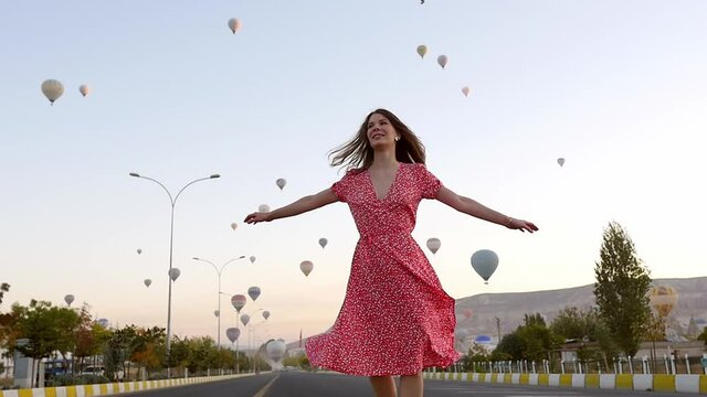 Traveler is whirling in a bright dress, looking at the balloons. Feeling of complete freedom, euphoria, achievement, happiness