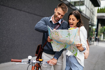 Happy smiling woman and man in love walking with map in the city