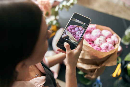 Close up photo florist at work. woman making photo of spring floral decorations.