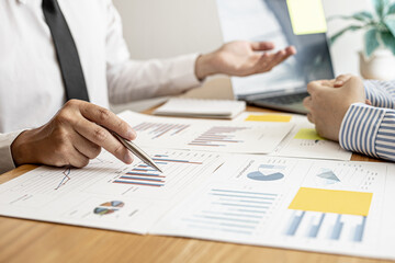 A close-up of a financial businessman holding a pen and pointing at the information sheet on his desk, reading the company's financials to make a financial plan. Financial concept.