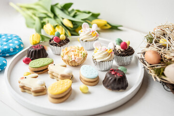 cute colorful spring easter egg shape cake tartlet muffin cupcake with yellow tulips easter concept 