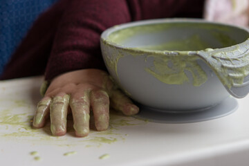 Cleanup time: messy bowl and baby hand after eating a green smoothie bowl (baby led weaning)