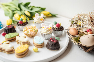 cute colorful spring easter egg shape cake tartlet muffin cupcake with yellow tulips easter concept 